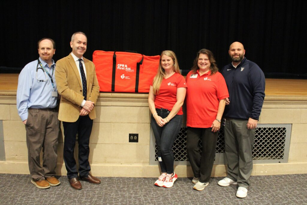 Individuals pose for photo with donated CPR kit.