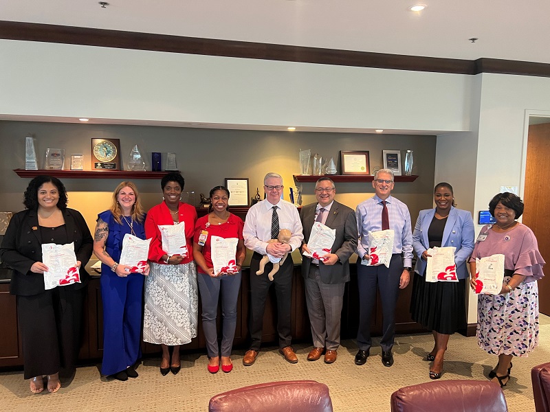 Group of executive leaders pose with infant CPR kits