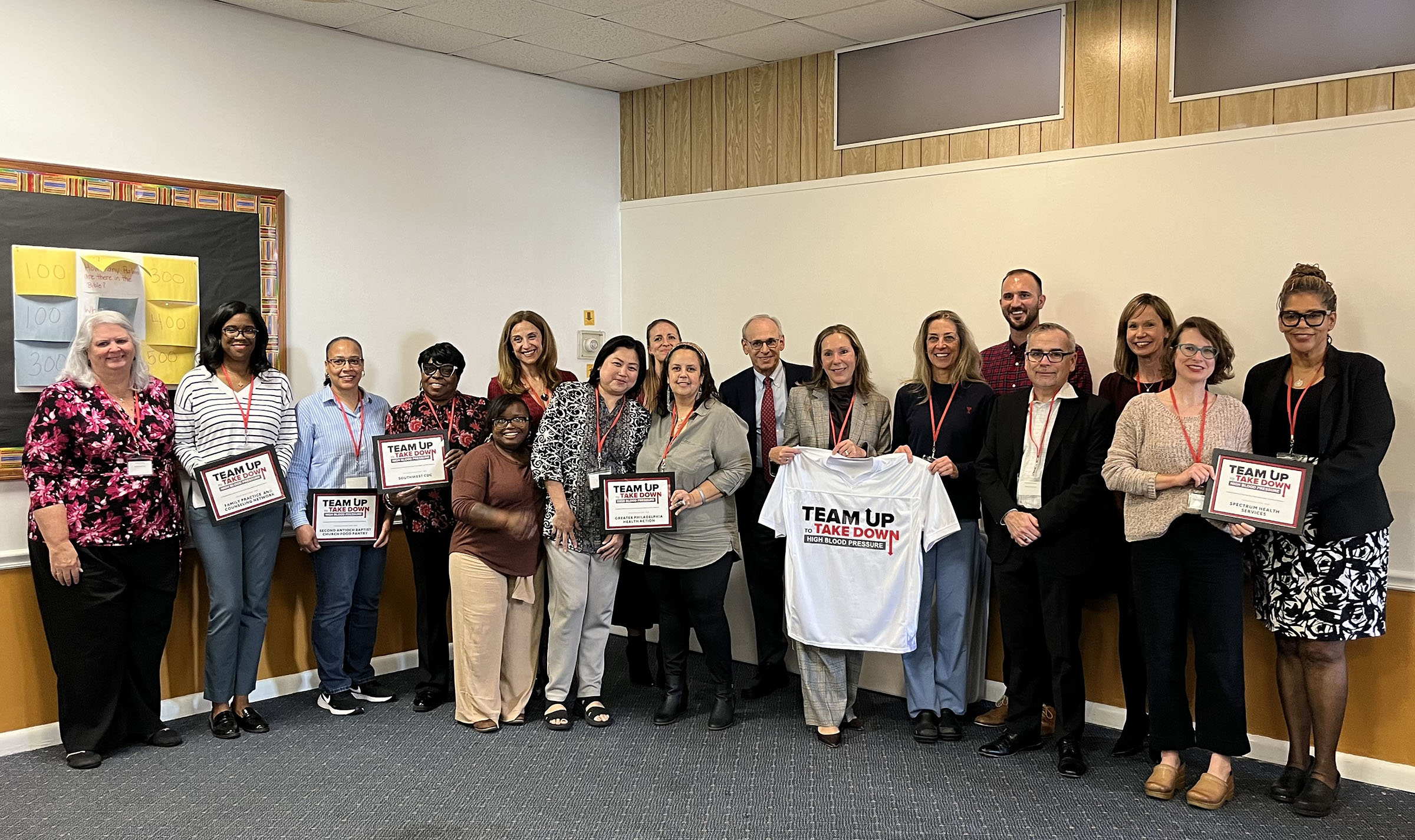 Group photo of AHA, Penn Medicine and community and clinical partners holding certificates and a ceremonial jersey