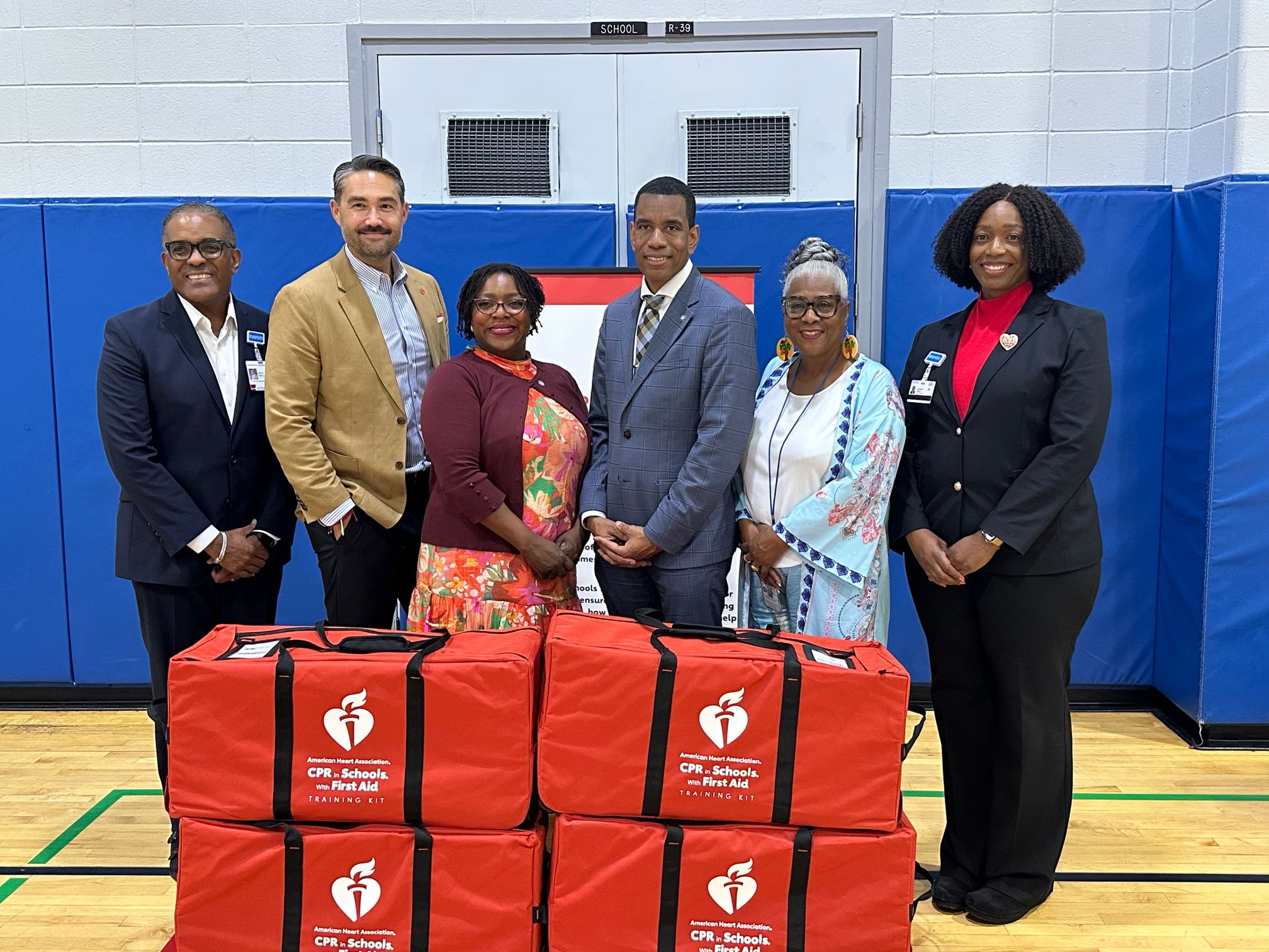 A group pf people in a gym stand with CPR in Schools Training Kits