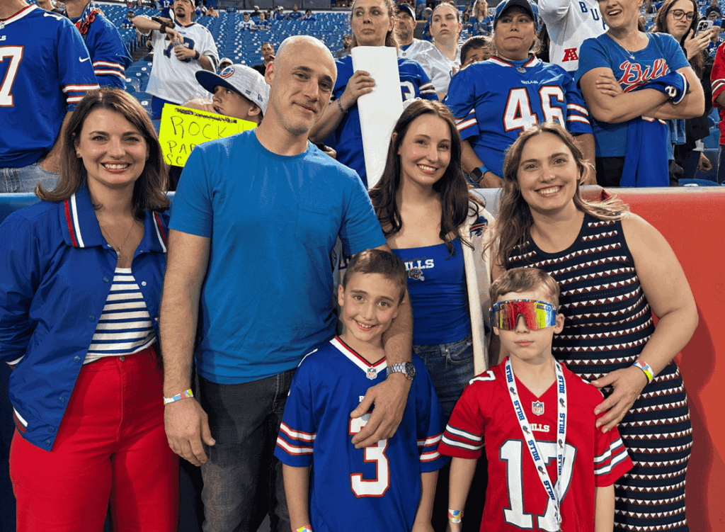 A family poses in front of the stands at a football stadium