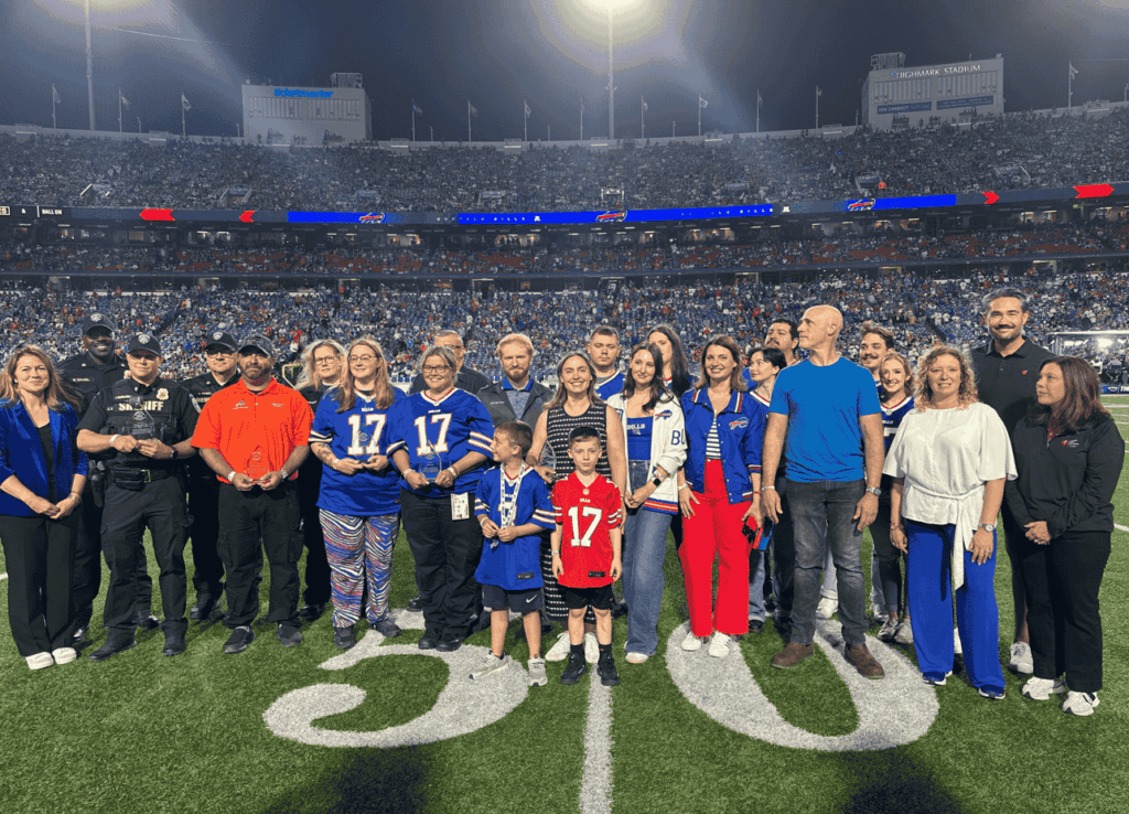 A large group of people stand on a field at a football stadium