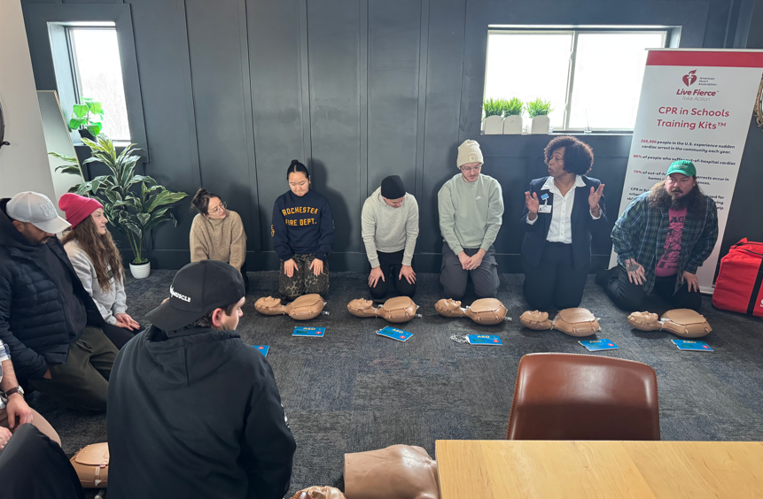 A group of people kneeling on the floor with CPR manikins