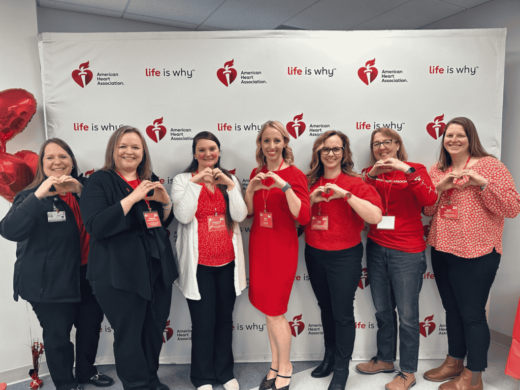 Seven women in front of a red and white backdrop