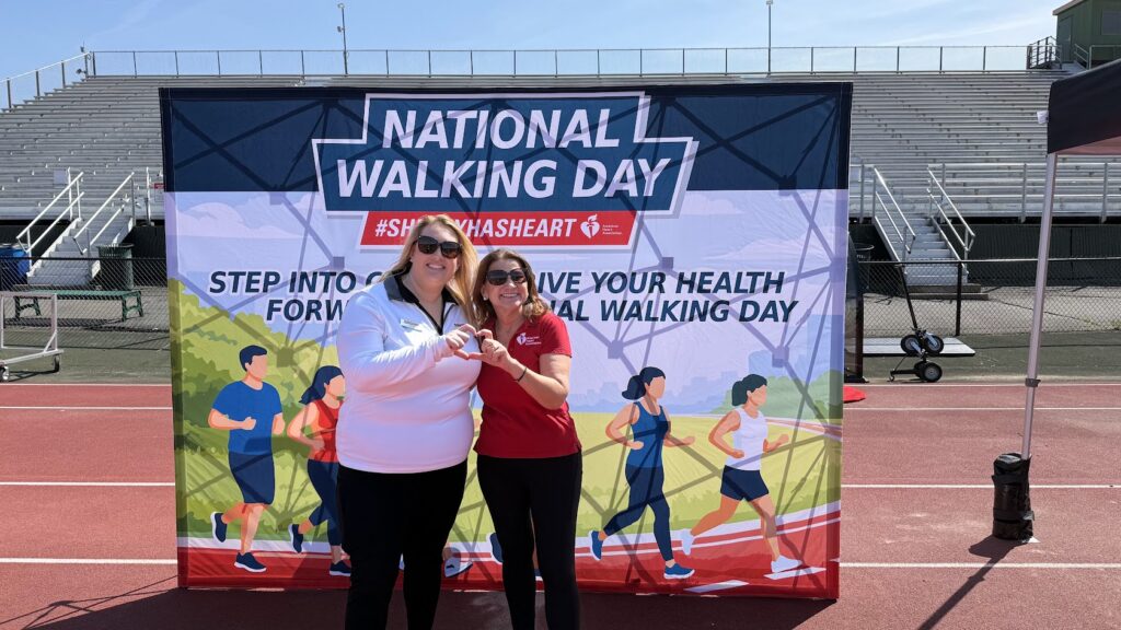 two women posing in front of National Walking Day banner