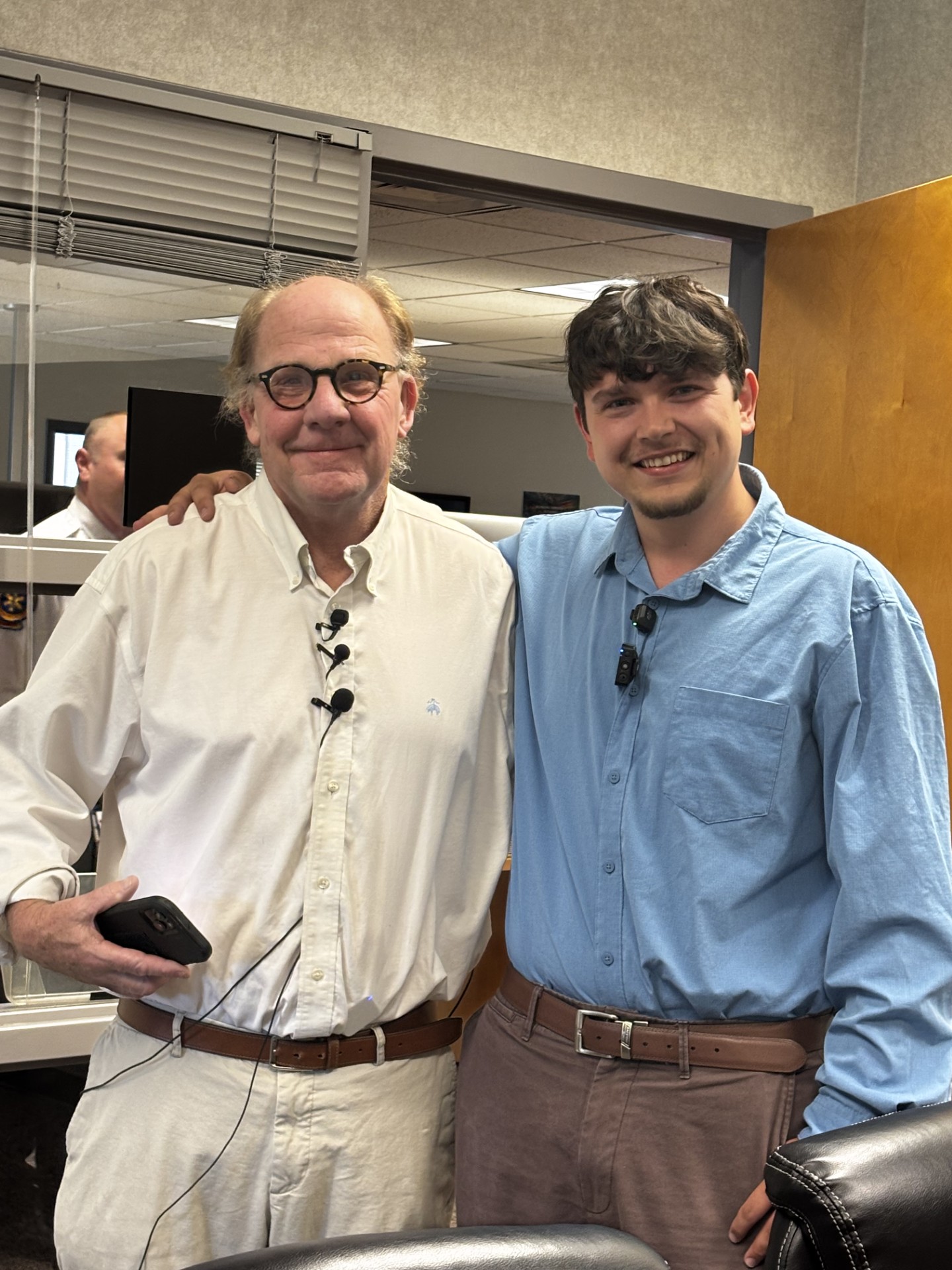 Two men stand together smiling