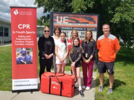 A group poses with a CPR in Schools kit